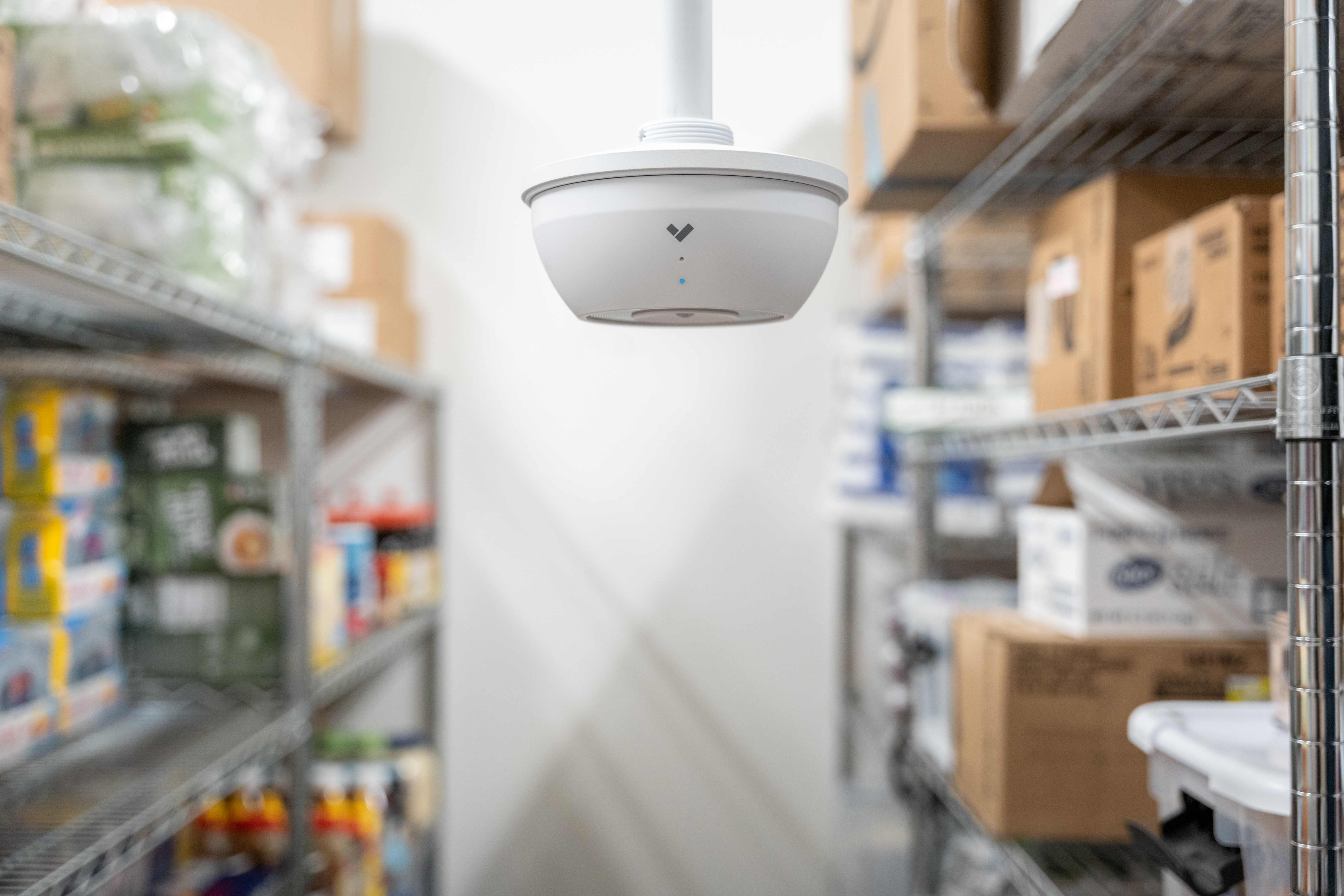 Ceiling-mounted environmental sensor in warehouse storage facility with shelving