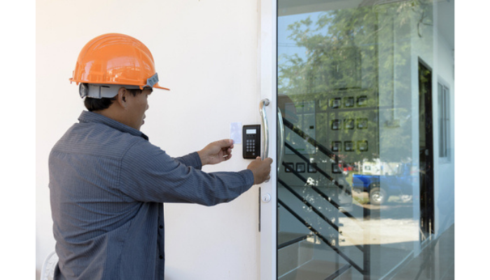 Professional technician in hard hat installing access control card reader at commercial facility