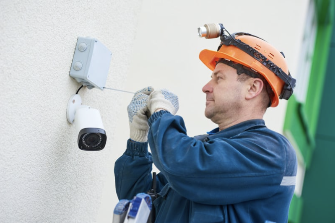 Technician installing security camera on wall